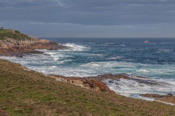 blue waters of Atlantic ocean breaking on the green coast of Coruna