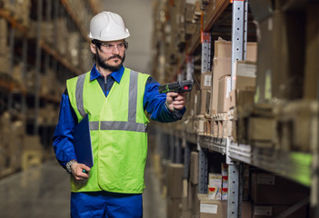 Warehouse worker checking cargo on shelves with scanner - obrazy, fototapety, plakaty