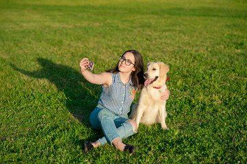 Pretty young woman with friendly golden retriever dog taking a selfie with a smartphone. Beautiful girl and her dog make self-portrait themselves by phone