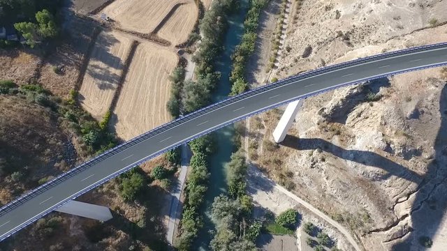 1080p Aerial, Flight over a highway bridge and down river village and olive orchards, Andalucia, Spain. Staright rows of olive trees and high rise bridge with going on cars. Way to Cordoba