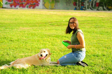 Woman training her dog golden retriever in the park