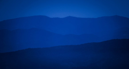 Photo depicting beautiful a foggy mystic mountains. Fog clouds at the pine tree mystical woods, morning. Europe, Bulgaria, mysterious Balkan landscape.
