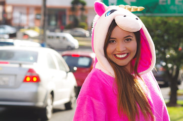 Portrait of a beautiful smiling young woman wearing an unicorn costume, at outdoors in the city of Quito