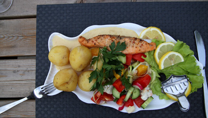 Lachs mit Kartoffeln, Gemüse und Zitrone angerichtet im Restaurant