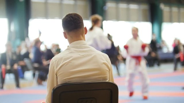 Martial art competitions- karate - judge coaches looking at female teenager's karate fighting