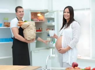 Beautiful pregnant woman with her husband in the kitchen