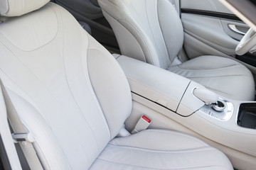 White leather interior of the luxury modern car. Leather comfortable white seats and multimedia. Steering wheel and dashboard. automatic gear stick. Car interior details