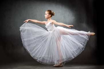 Adorable little ballerina dancing in studio. The girl is studying ballet.