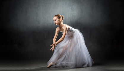 A young beautiful ballerina is posing in the studio. A little dancer. Ballet.