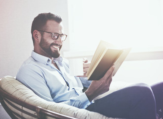 smiling handsome man reading book drinking coffee or tea