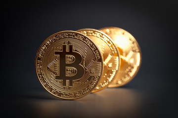 macro three golden bitcoins in a row on black background. virtual cryptocurrency concept