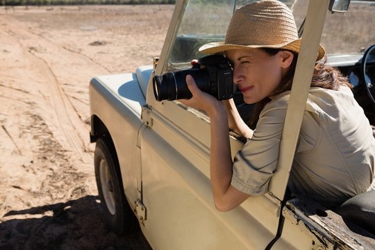 Woman photographing in off road vehicle 