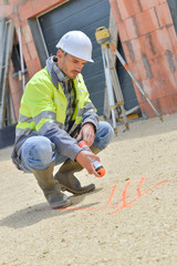 worker in a construction site drawing signs on the floor