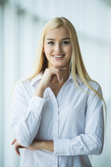Blonde Businesswoman crossed hands portrait in office with panormic windows. Business concept
