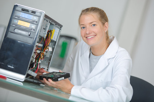 young smiling woman technician repairs a computer