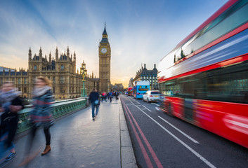 London, England - The iconic Big Ben and the Houses of Parliament with famous red double-decker bus and tourists on the move on Westminster bridge at sunset - obrazy, fototapety, plakaty