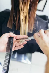 Photo sur Aluminium Salon de coiffure Gros plan d& 39 une femme dans un salon de coiffure qui se fait couper les cheveux par le coiffeur.