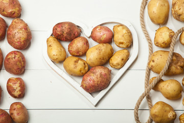 Raw potatoes on a white wooden background