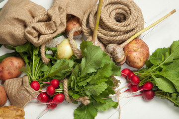 Raw radishes, onions and potatoes on a white wooden background
