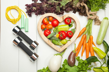 Sports and diet. Fresh vegetables, tomatoes, lettuce and carrot salad on a white wooden background