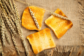 Toasts of bread and wheat on an old wooden background