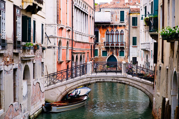 Fototapeta na wymiar Bridge over a narrow canal sidelined by old buildings in Venice