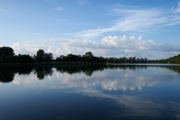 white cloudy blue sky at public park nearly the town with reflection on water