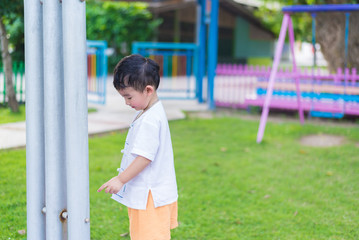 Obraz premium Little Asian kid playing and smiling at the playground under the sunlight in summer, shallow DOF