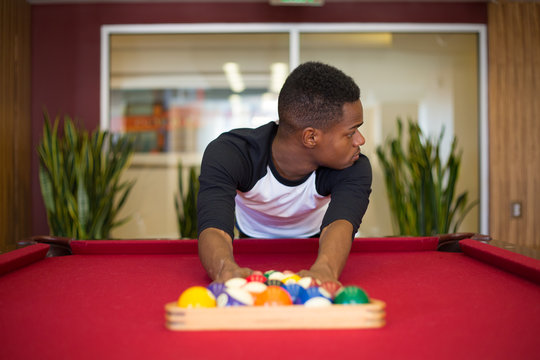 Closeup portrait, young man hanging out, playing billiards at red pool table, isolated indoors background