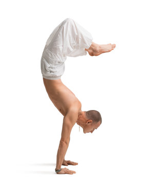 Mature shirtless muscular man doing yoga handstand