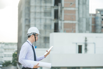 smiling young architect or engineering builder in hard hat with tablet over group of builders at construction site, architect watching some a construction, business, building, industry, people concept