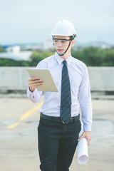 smiling young architect or engineering builder in hard hat with tablet over group of builders at...