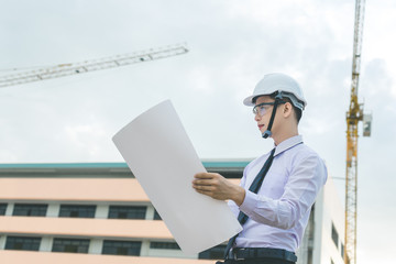 smiling young architect or engineering builder in hard hat with tablet over group of builders at...