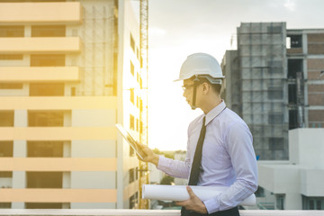 smiling young architect or engineering builder in hard hat with tablet over group of builders at...