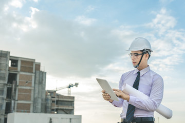 smiling young architect or engineering builder in hard hat with tablet over group of builders at construction site, architect watching some a construction, business, building, industry, people concept