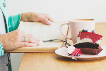 Woman with a cup of cappuccino and a piece of dessert on the plate
