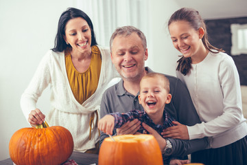 Fototapeta na wymiar Family carving big orange pumpkin for Halloween and having fun
