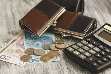 Polish zloty with little wallets and calculator on the wooden background