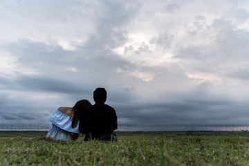 Naklejka na ściany i meble woman and man relax and siting on park with sunset and cloud sky thinking and concentrate in sunset background with copy space concept.