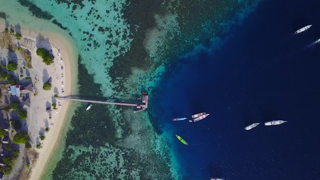 Beautiful aerial landscape footage of Kanawa Island Resort with turquoise water, wooden pier, and boats at East Nusa Tenggara, Indonesia. Shot in 4k resolution