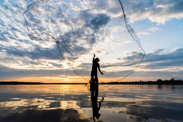 Silhouette of Fishermen throwing net fishing in sunset time at Wanon Niwat district Sakon Nakhon Northeast Thailand. © Joeahead