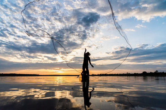 Silhouette of Fishermen throwing net fishing in sunset time at Wanon Niwat district Sakon Nakhon Northeast Thailand.