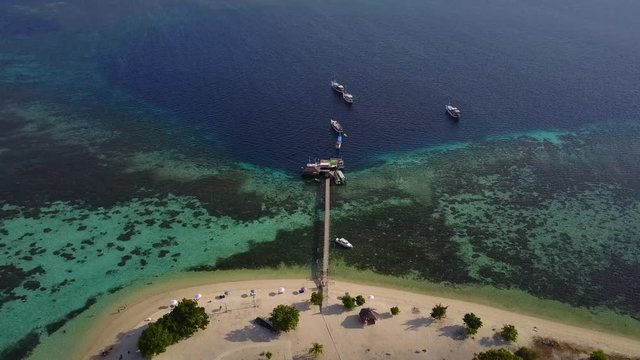 Beautiful aerial view footage of a wooden jetty and boats on the Kanawa Island Resort, East Nusa Tenggara, Indonesia. Shot in 4k resolution