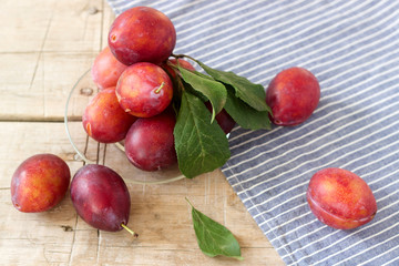 Plums in a plate on a wooden table, rustic style, selective focus.