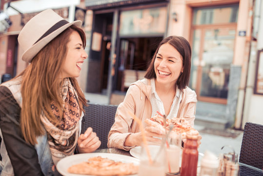 Two young woman eating pizza