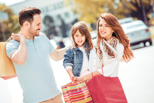Family couple with child and shopping bags outdoors.