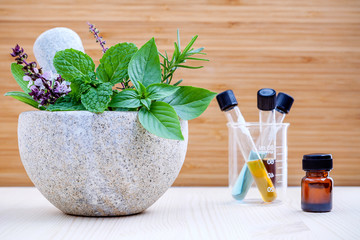 Alternative health care and herbal medicine .Fresh herbs and aromatic oil with mortar and pestle on wooden background. Various herbs rosemary ,sage ,sweet basil leaves and green mint branch.
