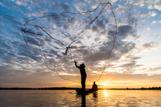 Silhouette of Fishermen throwing net fishing in sunset time at Wanon Niwat district Sakon Nakhon Northeast Thailand.