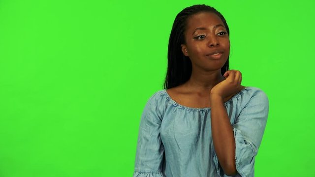 A young black woman covers her eyes with her hands, stops and looks around in confusion - green screen studio