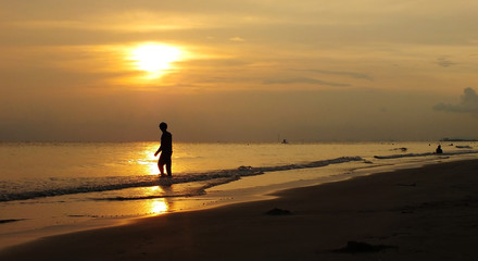 Fototapeta na wymiar A man standing by the sea The sunset.